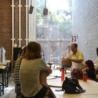 An art professor making a piece of pottery while a group of students observes