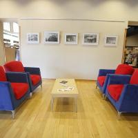 A wooden coffee table with two blue and red chairs on either side 