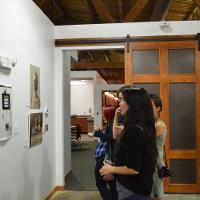 Several people at an art museum looking at small paintings 