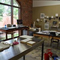 An art classroom with big desks and supplies 