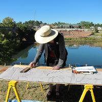 A person working outside on a large wooden art piece 