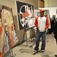 Two men in an art gallery discussing the large paintings 