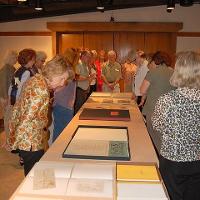 Adults looking down at paintings and drawings lain on a table 