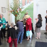 A large flower display with several people gathered next to it, smiling and chatting 