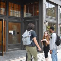 Three students chatting outside the entrance to a building 