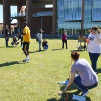 Students in groups on a grassy lawn 
