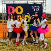 several female students posing in front of a sign, neon colors 