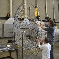 Two students working on a circular metal project 