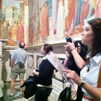 A student looking a large mural, a tour book in her hand 