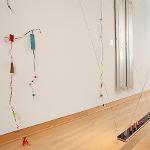 Colorful wire and bead sculptural elements suspended on gallery wall