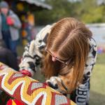 Close-up of a person painting vivid red and orange patterns on a mural.