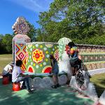 Child painting colorful circular designs on a large outdoor structure.