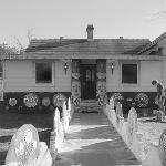 Black and white photo of Eddie Martin's house entrance with face totems and decorated walkway