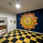 Interior room with large colorful mandala medallion on dark blue wall and checkered floor
