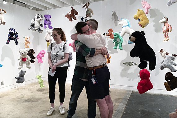 multiple students in a gallery surrounded by teddy bears