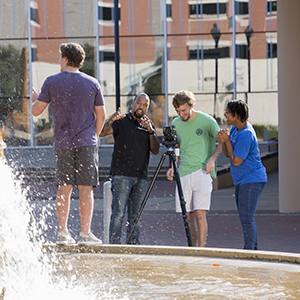 a group of people using a video camera with another person standing away from them