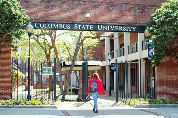 a student walking through a large brick gate