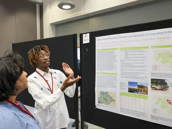 a student presenting his research to a lady