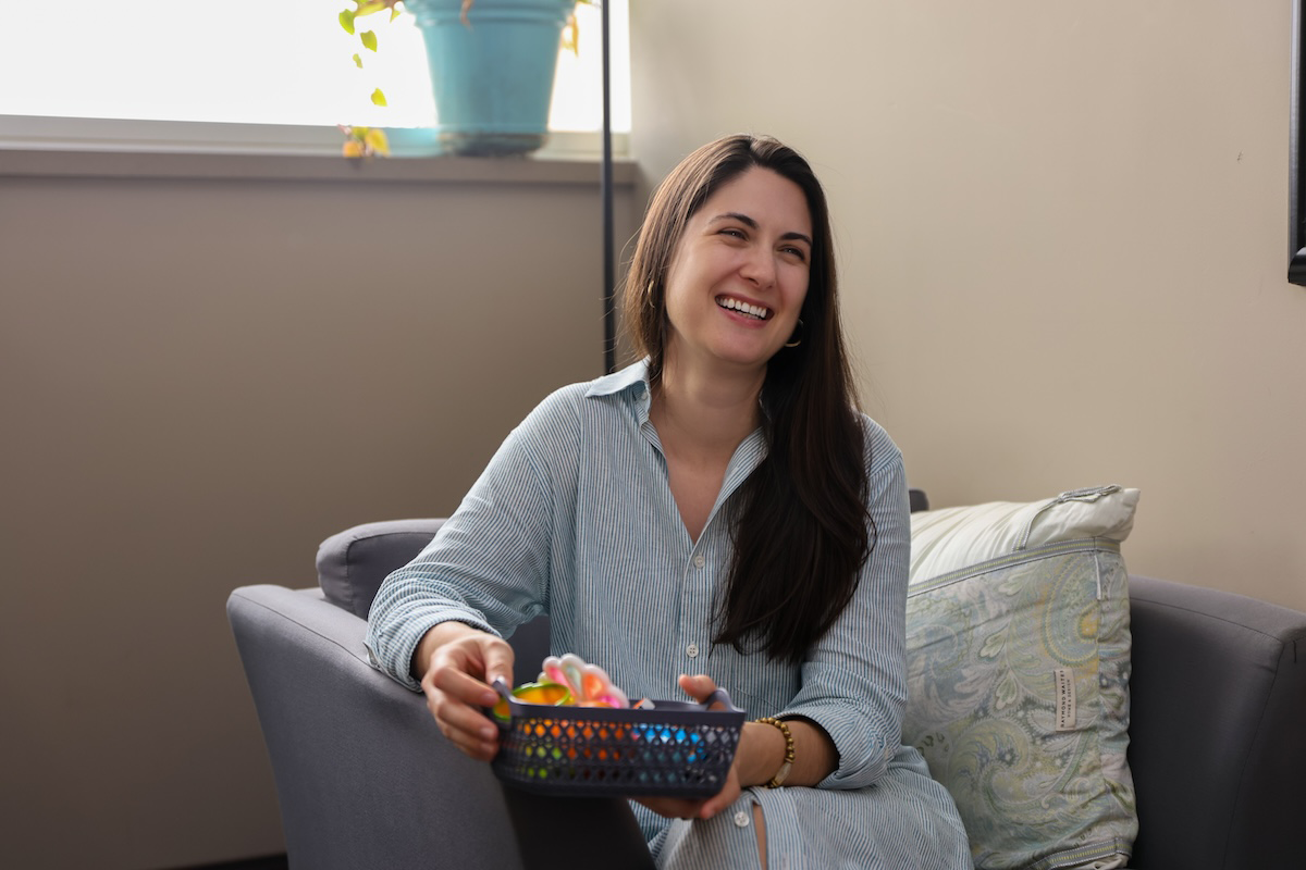 a counselor sitting in a chair smiling and holding a basket of items