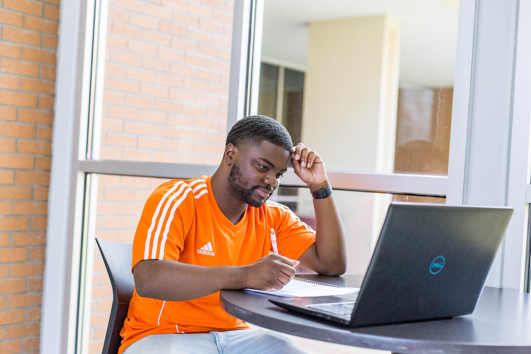 a mail student sitting at his laptap