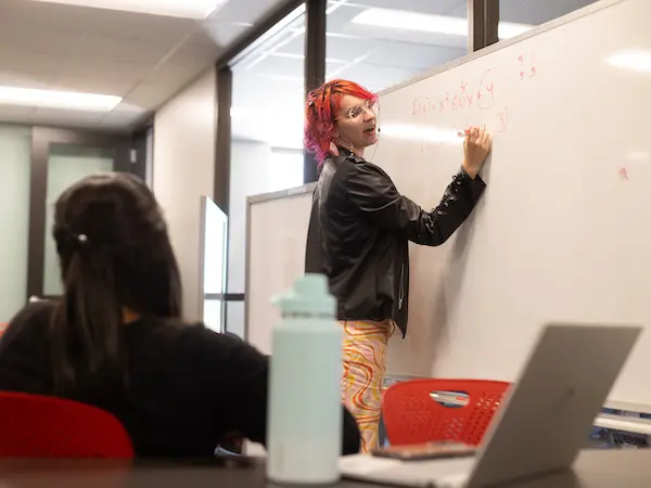 a young woman at a white board teaching