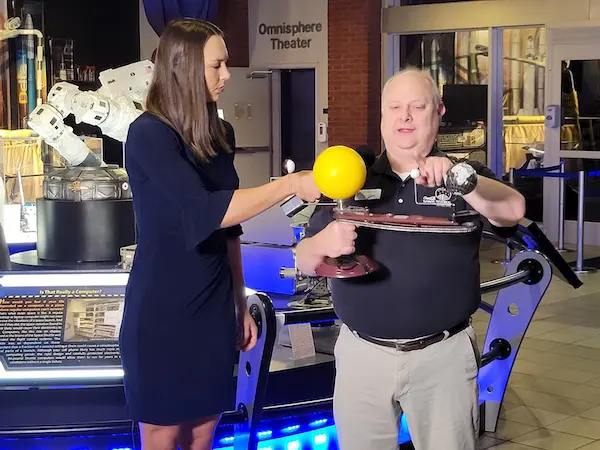 a man showing a reporter a solor system model