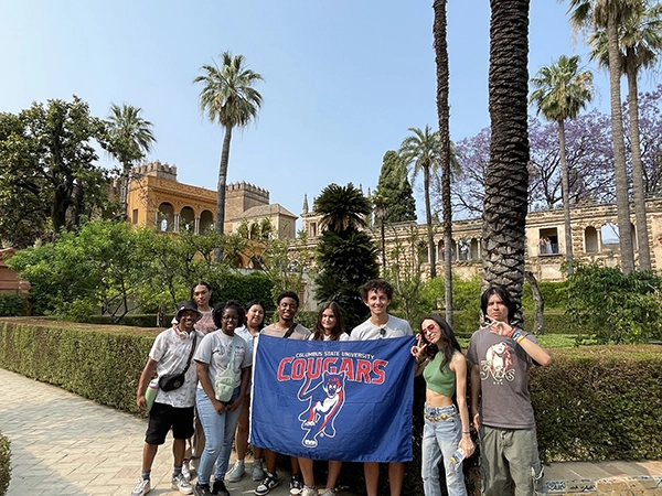 Students standing with a CSU Banner at the Alcazar Gardens.