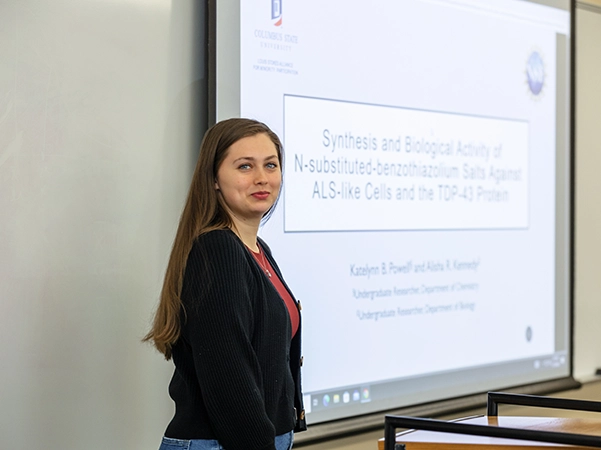A professor standing by the presentation that she is preparing to give her class.