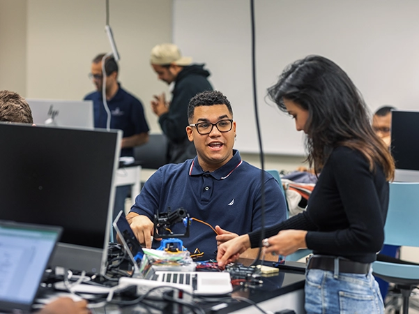 Two students laughing and working together in a bright classroom.