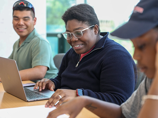 A student studying in a bright classroom on her personal laptop.