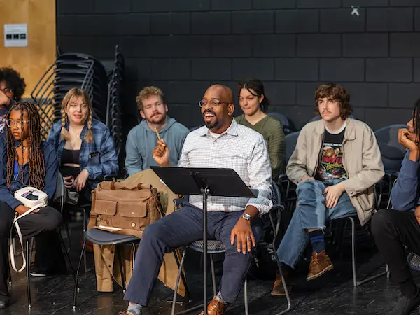 A theatre professor excitedly talking to one of his students.
