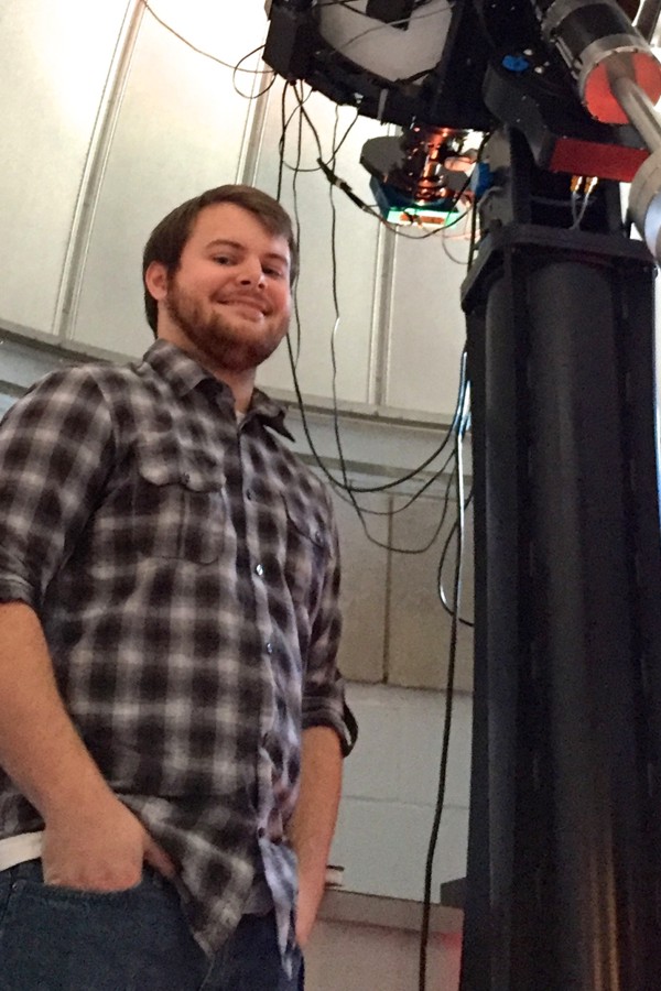 a student standing in front of a telescope