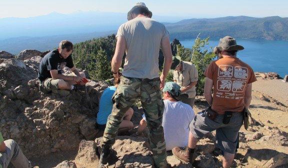 Several students and professors sitting on a rock
