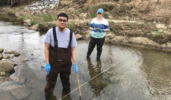 One male and one female student standing in a creek