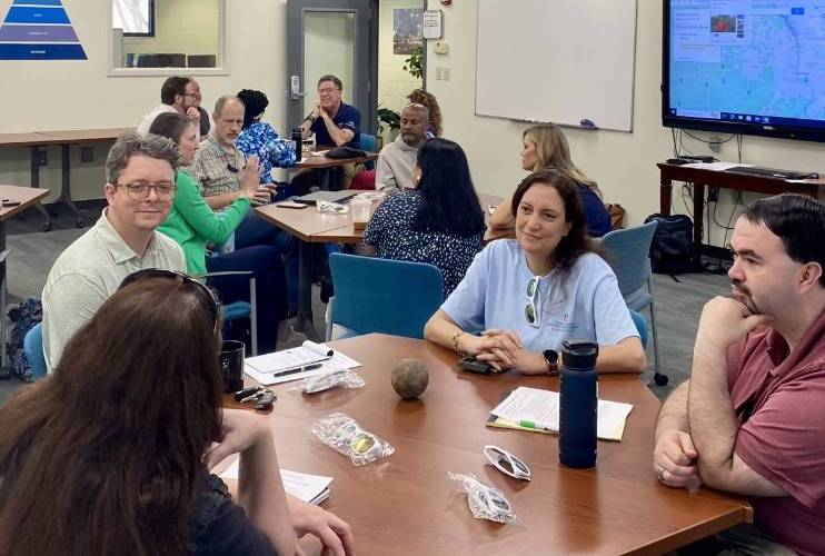 Faculty gathered at tables in the Experential Learning Lab conversing