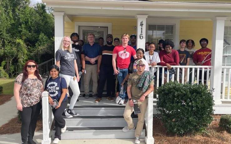 Group of students on the front porch of a yellow house