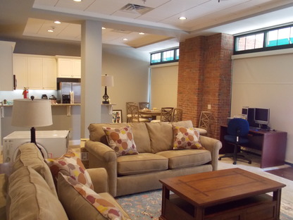 a room with several couches and a kitchen in the background