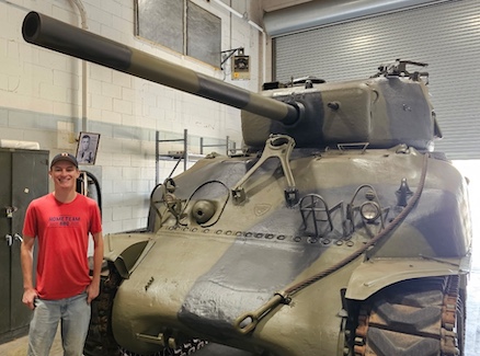 A student standing next to an army tank