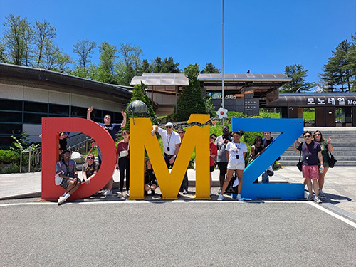 several people posing with giant letters that spell out DMZ