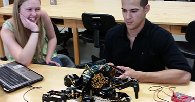 two students looking at a robot on a table