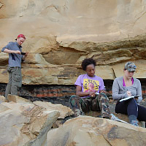 several students sitting on a rock face