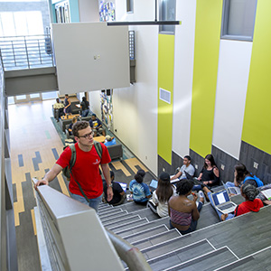 a male student walking up a staircase with several students sitting on it