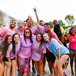 Group of students covered in pink powder laughing at a color party event