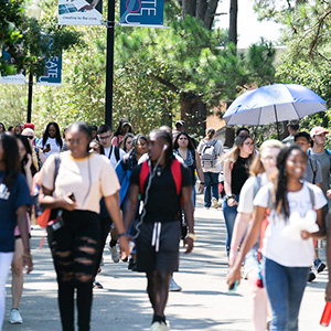 Large group of students walking along a busy campus pathway