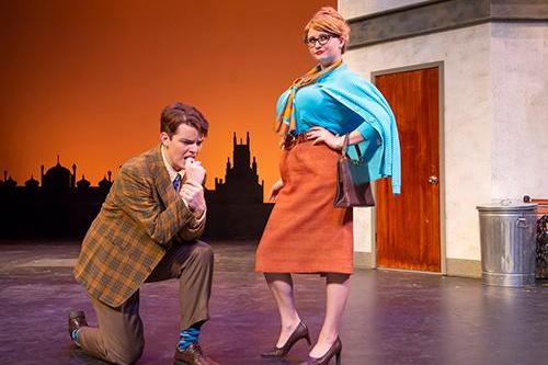 two people standing on a stage, one person kneeling