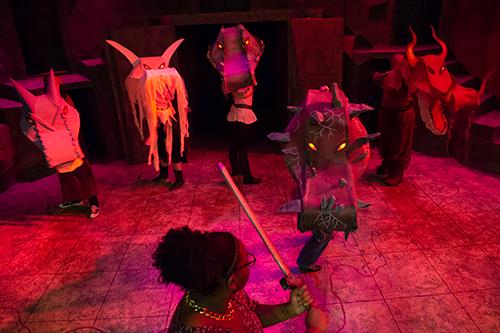 a girl holding a prop sword facing several monsters