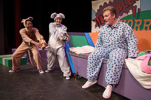 three people on a stage, two in animal costumes