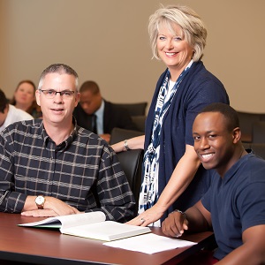 a woman standing between two male students